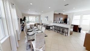 A modern kitchen with a central island, bar stools, and a dining area with a round table and chairs. - Encore Resort at Reunion 7511 (Kissimmee)