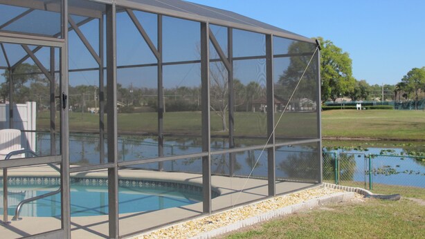 Un área de piscina moderna al aire libre con cerramiento de vidrio y vistas despejadas del paisaje circundante.