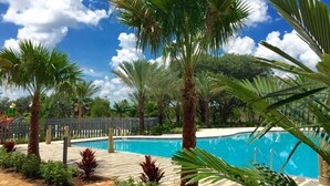 A swimming pool surrounded by palm trees and a brick pathway. - Festival Resort 342 (Davenport)