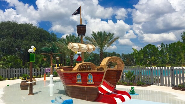 A pirate ship-themed water play area with a slide, a ship's wheel, and a lifebuoy. - Festival Resort 342 (Davenport)
