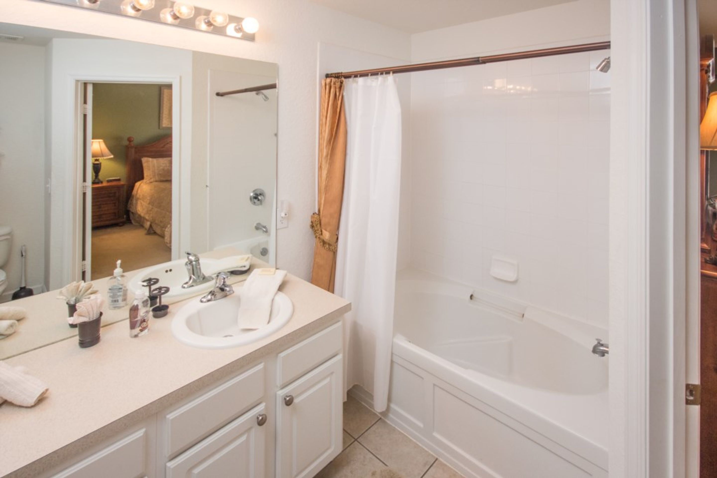 A bathroom with a sink, mirror, and bathtub.