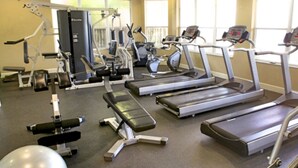 Ein Fitnessstudio mit Laufbändern, Krafttrainingsgeräten und Kurzhanteln.