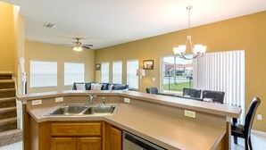 A kitchen with a central island, built-in dishwasher, and a dining area with a chandelier. - Bella Vida 4561 (Kissimmee)