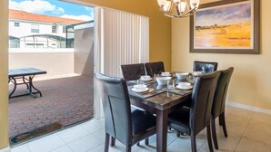A dining area with a table set for four, chairs, and a chandelier. - Bella Vida 4561 (Kissimmee)