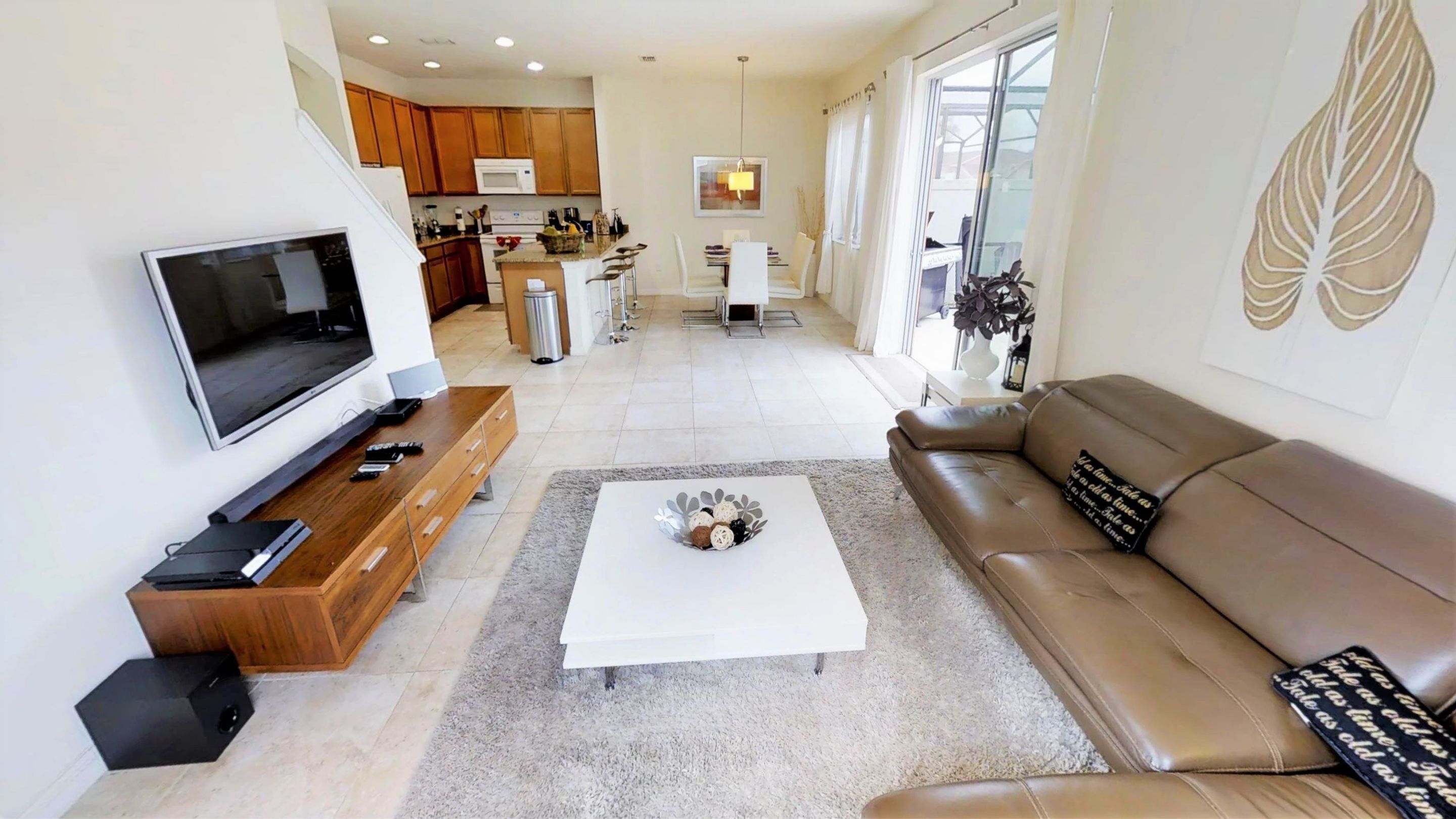 A modern living room with a flat-screen TV, wooden entertainment unit, and a brown leather sofa.