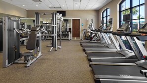 Una palestra con tapis roulant, macchinari per pesi e uno specchio a parete.