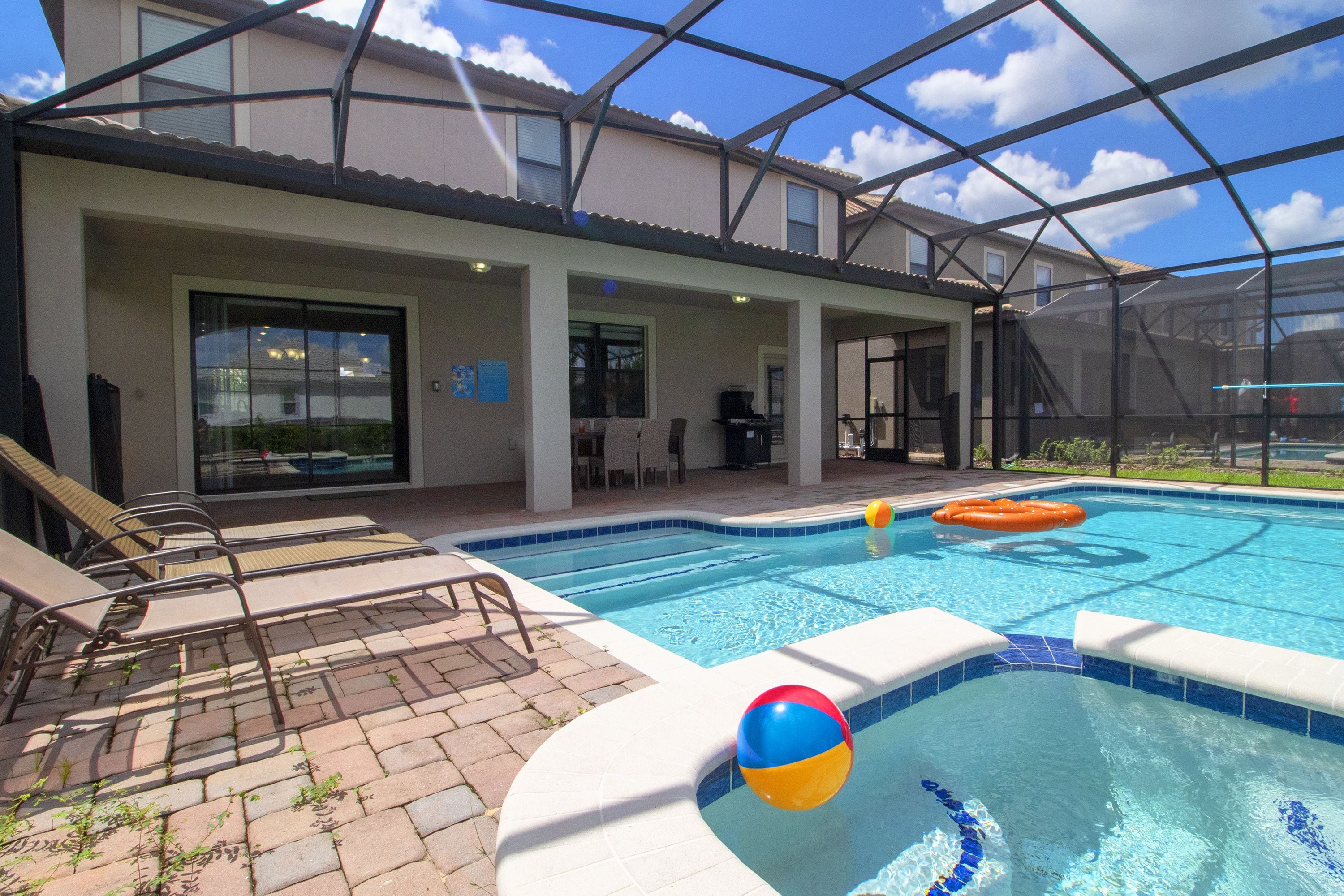 A pool area with lounge chairs, a hot tub, and a covered patio.