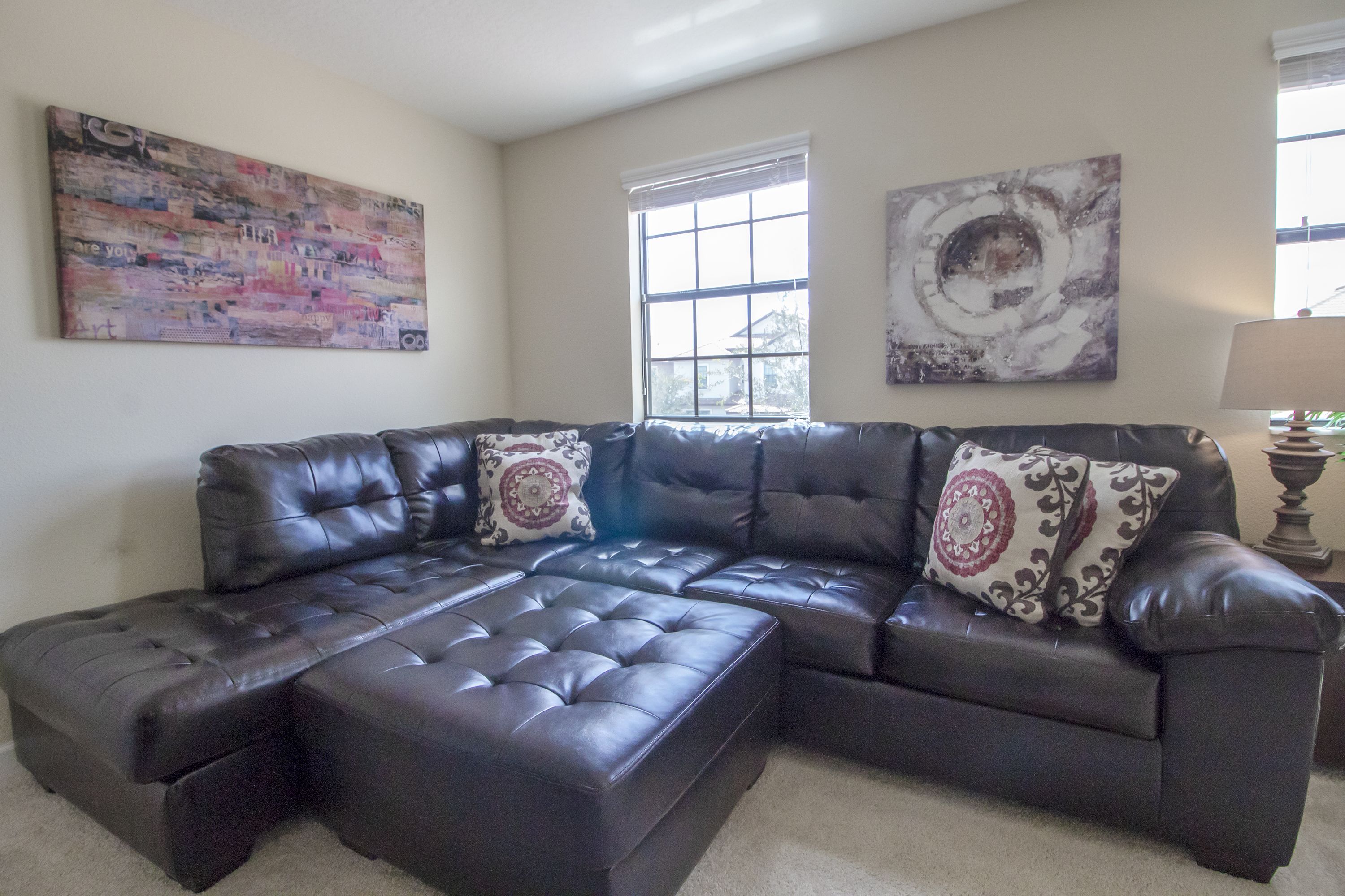 A sectional sofa with a chaise, two decorative pillows, and a window with blinds.