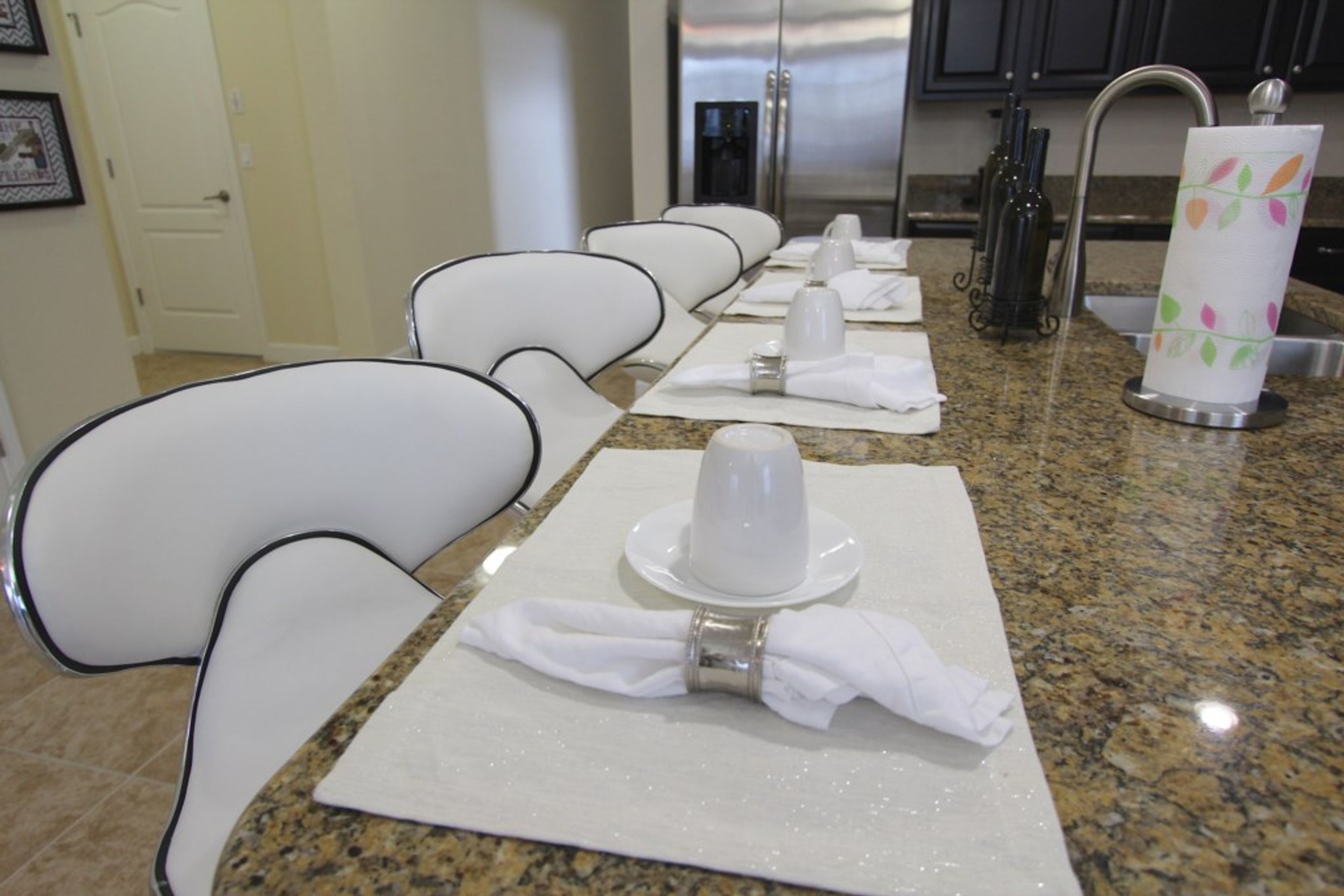 A hotel dining area with a long table set for a meal, white chairs, and a decorative paper towel holder.