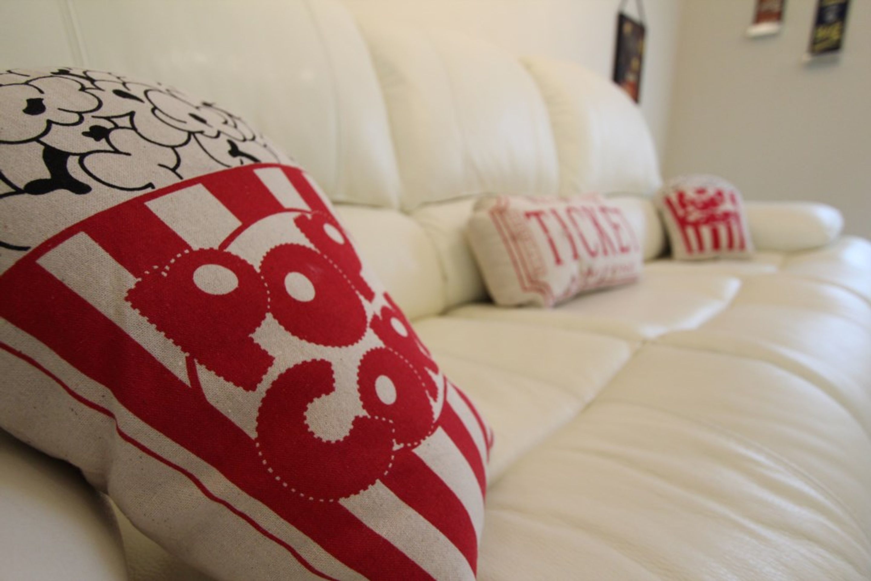 Un canapé blanc recouvert de tissu, agrémenté de coussins décoratifs aux motifs rouges et blancs.