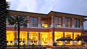 A modern hotel with a spacious outdoor area featuring lounge chairs and umbrellas, a well-maintained garden, and a large building with multiple windows. - Regal Oaks 2714 (Kissimmee)