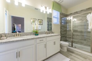 Ein modernes Badezimmer mit einer Granit-Arbeitsplatte, einer Duschkabine aus Glas und einer weißen Toilette.