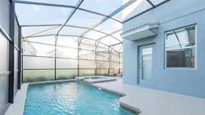 Piscina com estrutura de vidro, banheira de hidromassagem e porta que dá para um espaço de varanda coberto.