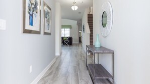 Um corredor com quadros nas paredes, uma escada e um console com um vaso.