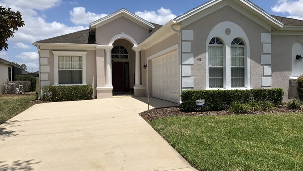 A two-story house with a front garage, a driveway, and a well-maintained lawn. - Calabay Parc 410 (Davenport)