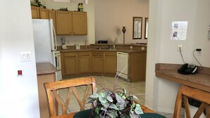 A kitchen with wooden cabinets, a refrigerator, a dishwasher, and a telephone on a counter. - Calabay Parc 410 (Davenport)