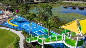 Ein Wasserpark mit Rutschen und Pools, umgeben von viel Grün und einer Brücke.