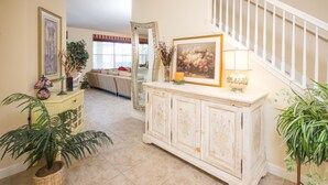 A living room with a white cabinet, a large mirror, and a staircase. - The Shire at West Haven 1012 (Davenport)
