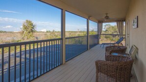 A balcony with wicker furniture, a view of the surrounding landscape, and a ceiling fan. - The Shire at West Haven 1012 (Davenport)