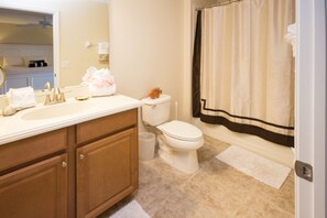 A bathroom with a toilet, sink, and shower curtain.