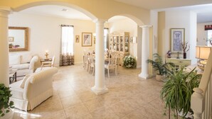 A spacious living area with a dining table and chairs, a sofa, and a chandelier. - The Shire at West Haven 1012 (Davenport)