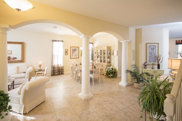 A spacious living area with a dining table and chairs, a sofa, and a chandelier.