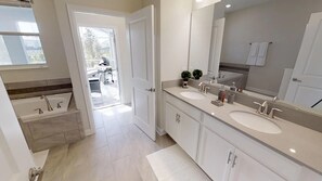 A modern bathroom with two sinks, a large mirror, and a shower area. - Champions Gate 1548 (Davenport)
