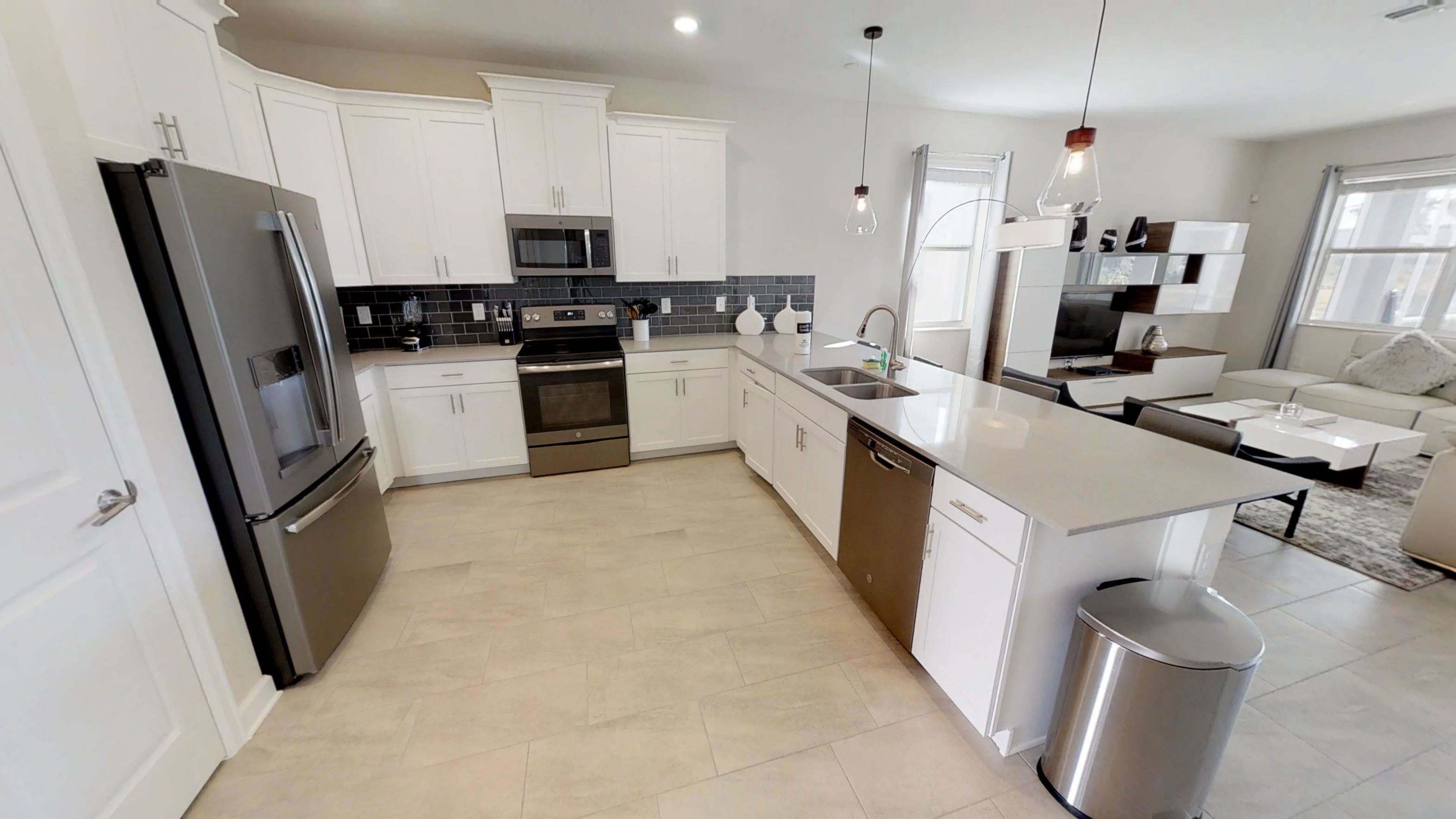 A modern kitchen with white cabinets, stainless steel appliances, and a central island.