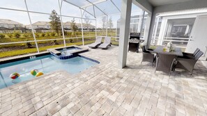 A covered outdoor swimming pool with lounge chairs and a barbecue area. - Champions Gate 1548 (Davenport)
