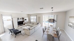 A modern living room with a sofa, TV, and dining area. - Champions Gate 1548 (Davenport)