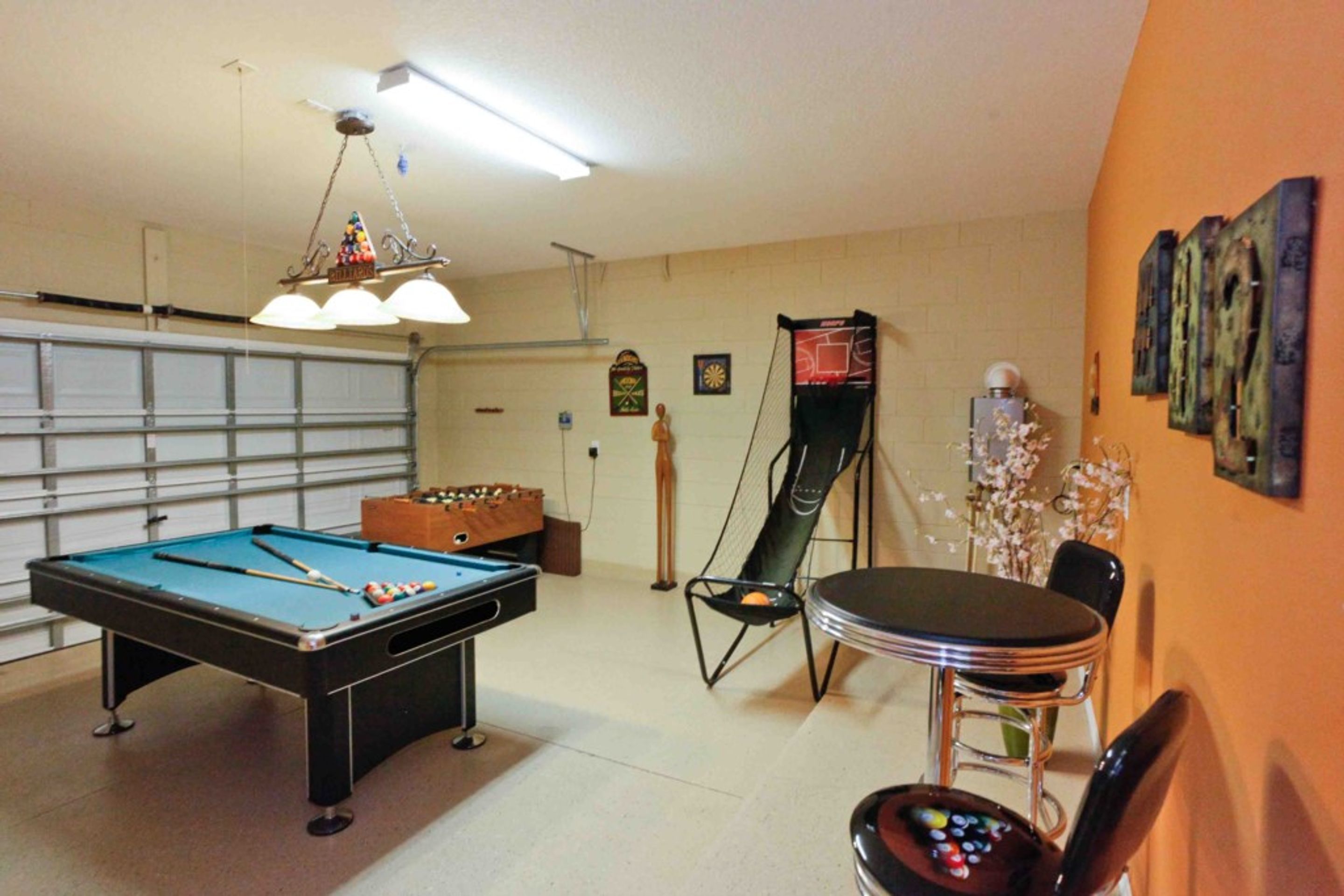 A pool table, a foosball table, a chair, and a table with a remote control.