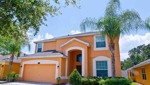 A two-story house with a garage, a small front yard, and a palm tree. - Veranda Palms 2514 (Kissimmee)