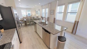 A modern kitchen with granite countertops, stainless steel appliances, and a central island with a sink. - Encore Resort at Reunion 341 (Kissimmee)