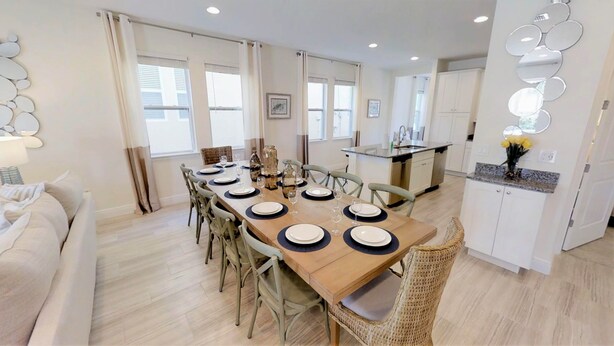 A modern dining area with a wooden table set for six, surrounded by wicker chairs. - Encore Resort at Reunion 341 (Kissimmee)