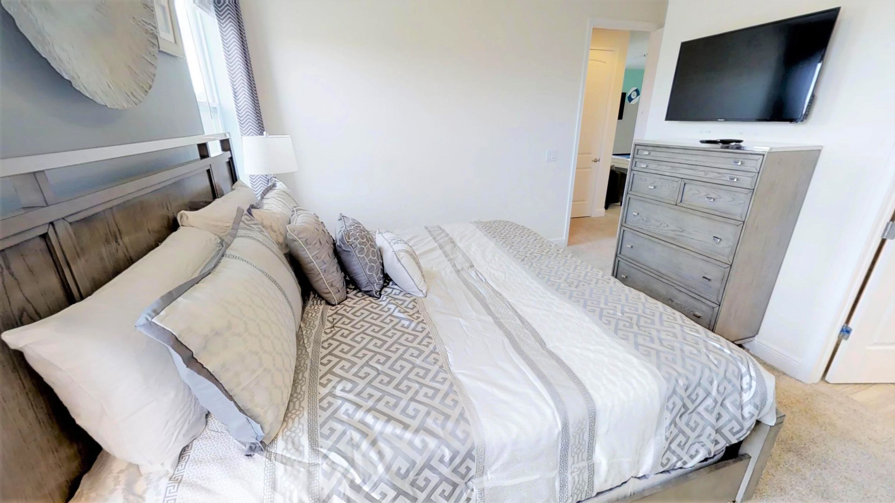 Une chambre à coucher comprenant un lit, une commode, un téléviseur et une couvre-lit à motifs.