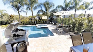 A pool area with a hot tub, grill, and seating area with umbrellas. - Encore Resort at Reunion 341 (Kissimmee)