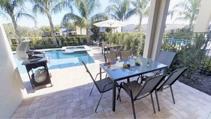 An outdoor patio with a pool, grilling area, and dining setup. - Encore Resort at Reunion 341 (Kissimmee)