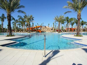 A swimming pool with a water slide, surrounded by palm trees and lounge chairs. - Solterra 4670 (Davenport)