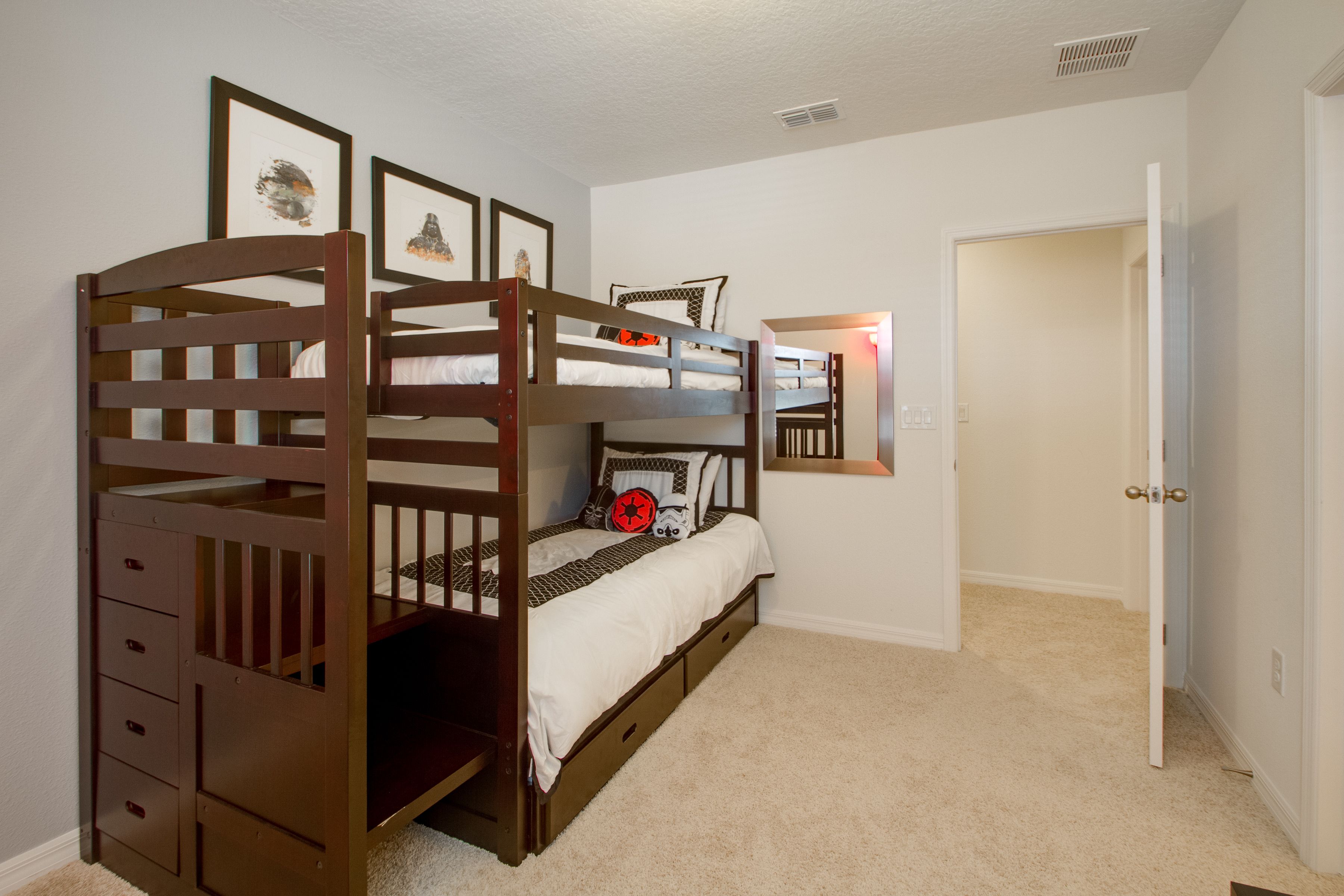 A bunk bed room with a door, a mirror, and a small dresser.
