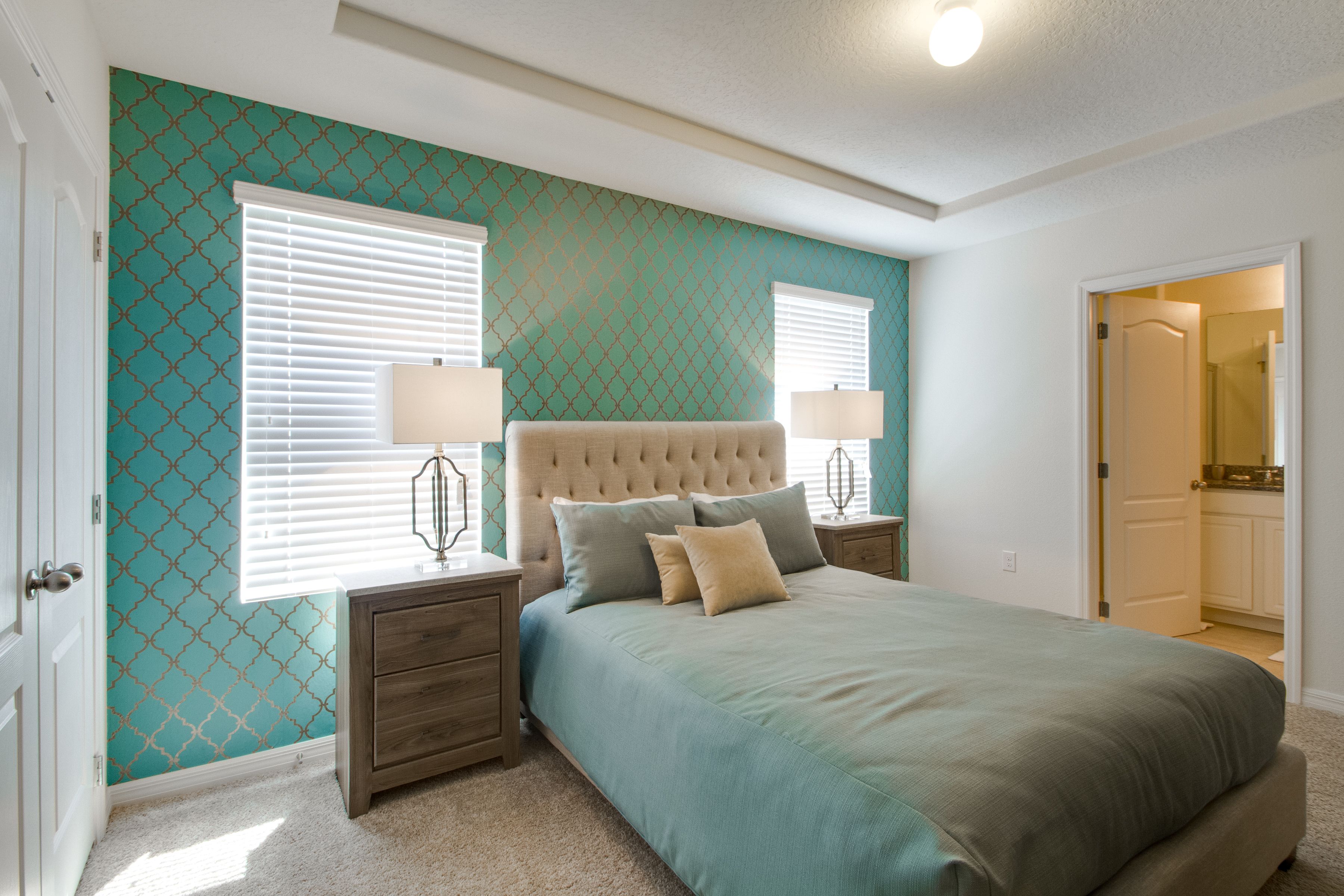 A bedroom with a large bed, two bedside tables with lamps, and a window with blinds.