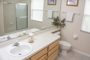 A bathroom with a sink, mirror, toilet, and shower.