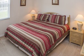 A bedroom with a large bed, two bedside tables with lamps, and a window with blinds.