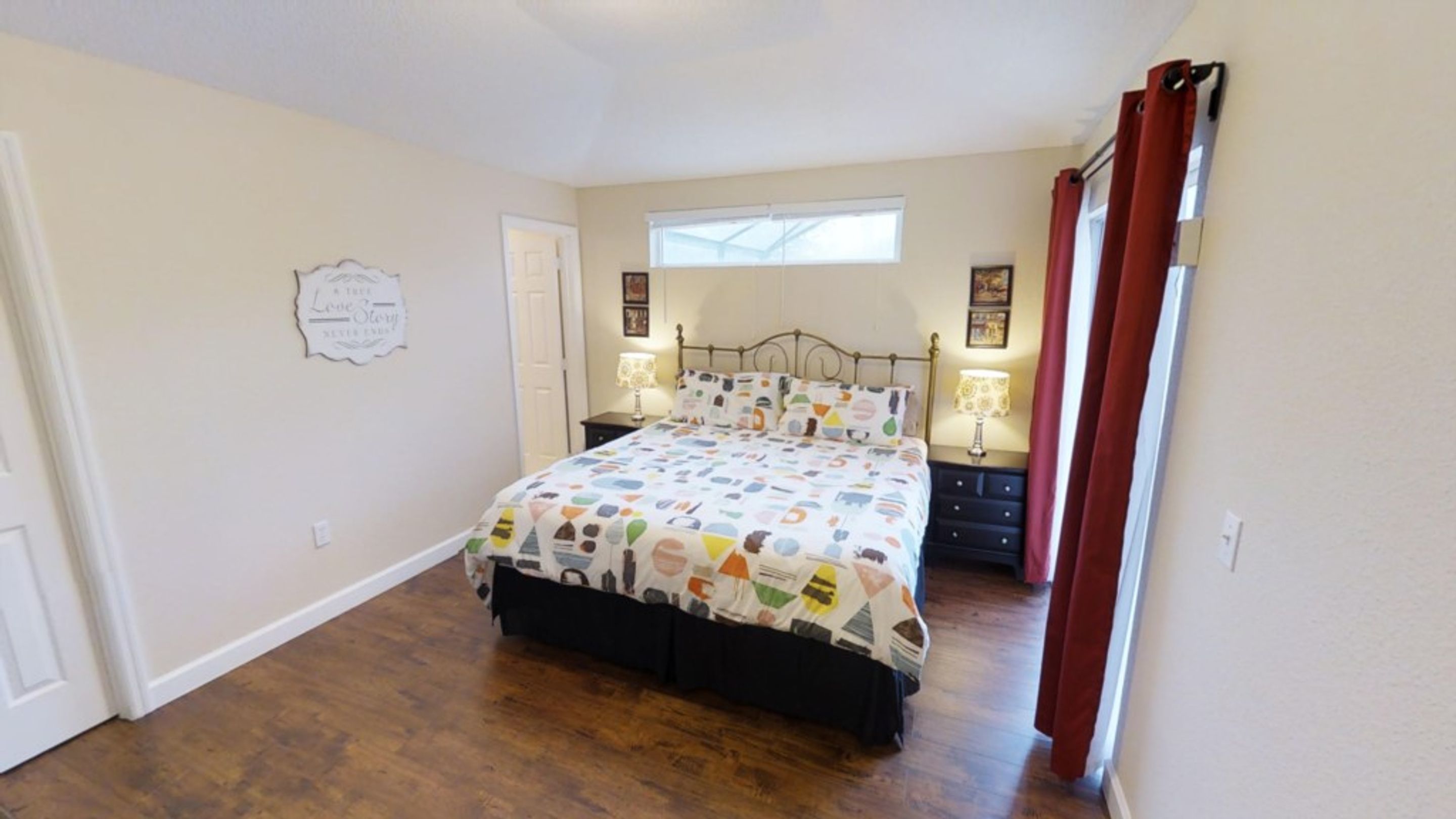 Quarto com cama, duas mesas de cabeceira, uma janela e uma porta.