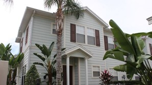 A two-story house with a front porch and a small garden with various plants.