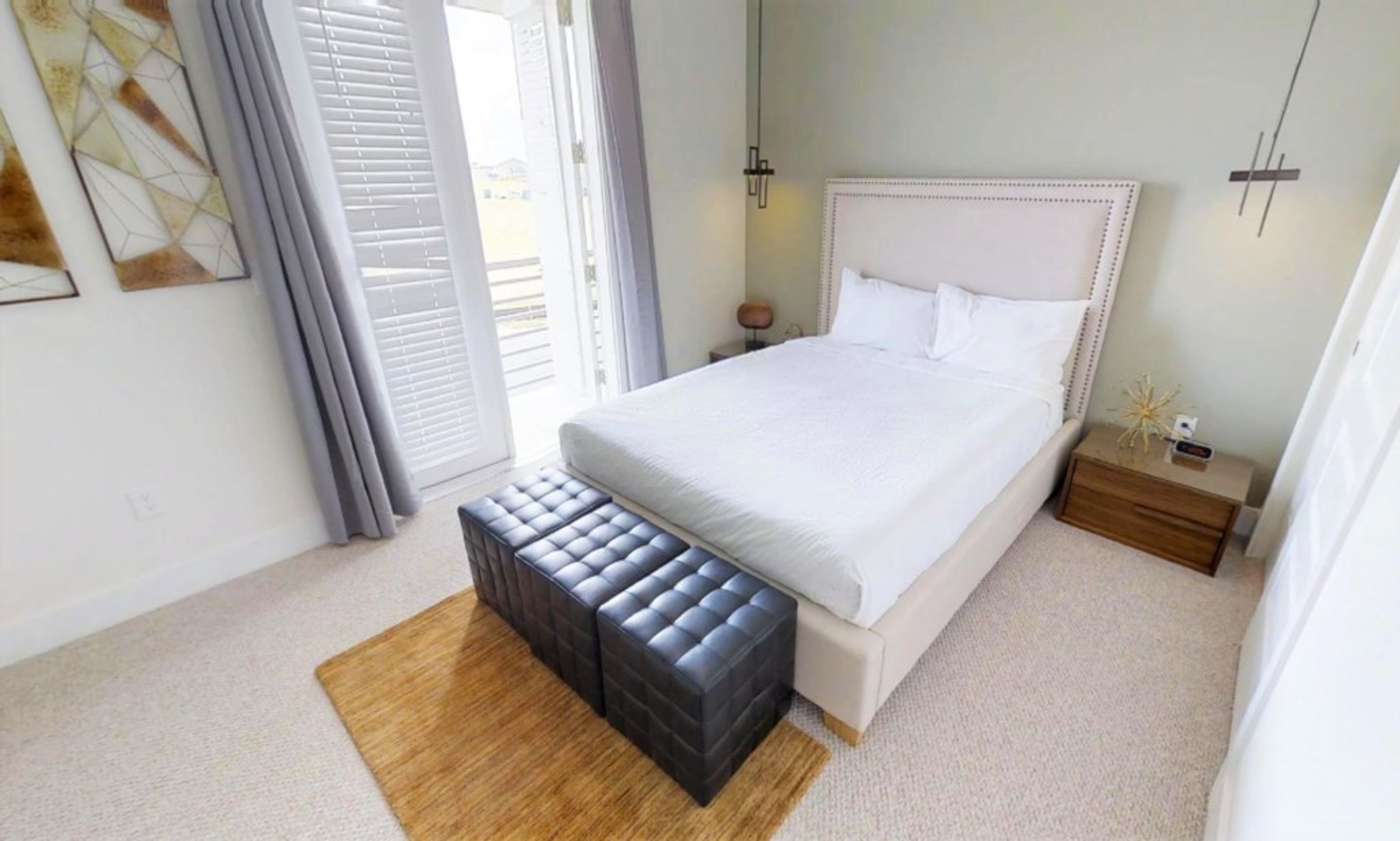 A bedroom with a bed, a bench, a nightstand, and a window with blinds.