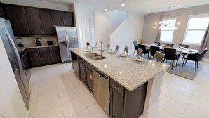 A modern kitchen with dark cabinets, stainless steel appliances, and a granite countertop. - Encore Resort at Reunion 281 (Kissimmee)