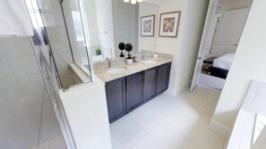 A modern bathroom with a glass shower enclosure, a double sink vanity, and a large mirror. - Encore Resort at Reunion 281 (Kissimmee)