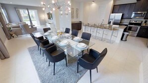 A modern kitchen with dark cabinets, stainless steel appliances, and a dining area with a glass table and black chairs. - Encore Resort at Reunion 281 (Kissimmee)