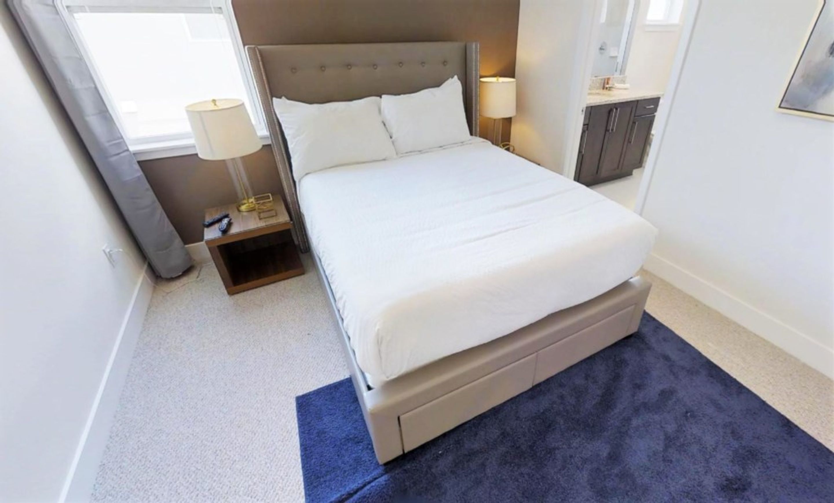 A neatly arranged bedroom with a bed, bedside tables, and a small cabinet.