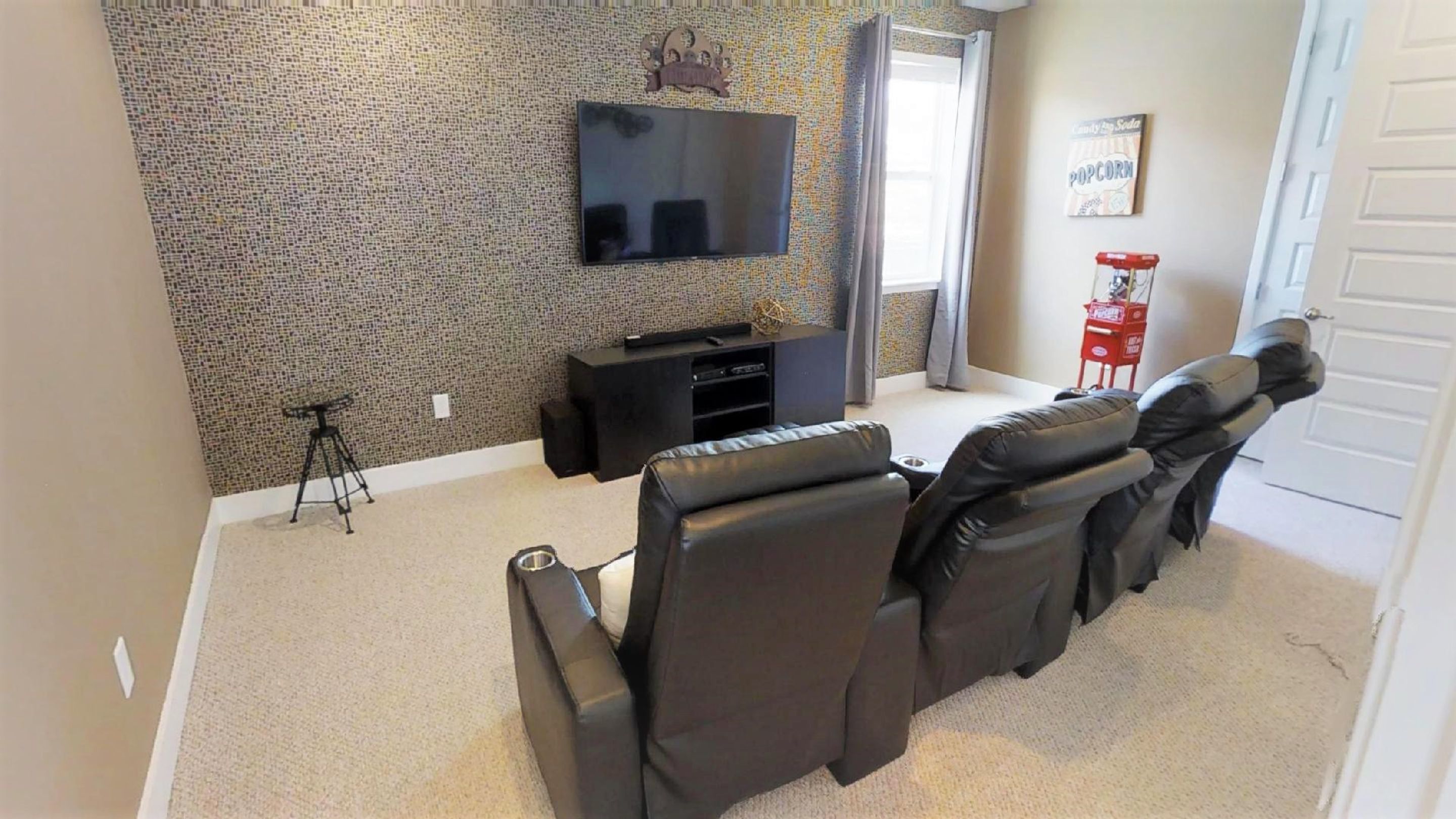 Una sala de estar con un televisor de pantalla plana montado en una pared con textura, un mueble negro para entretenimiento y un sofá reclinable.